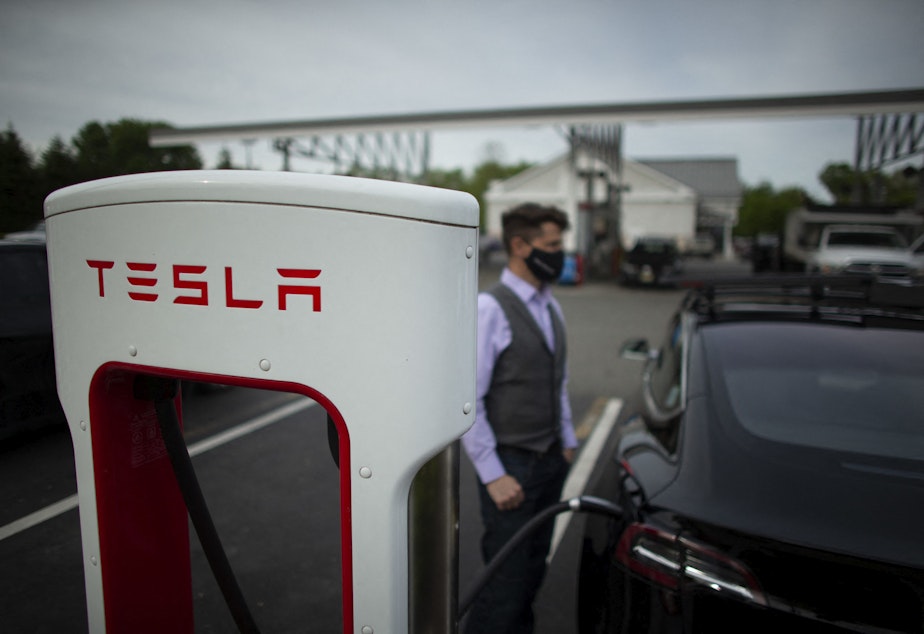 caption: Ben Rich charges his Tesla vehicle at a super charging station in New Jersey. (KENA BETANCUR/AFP via Getty Images)