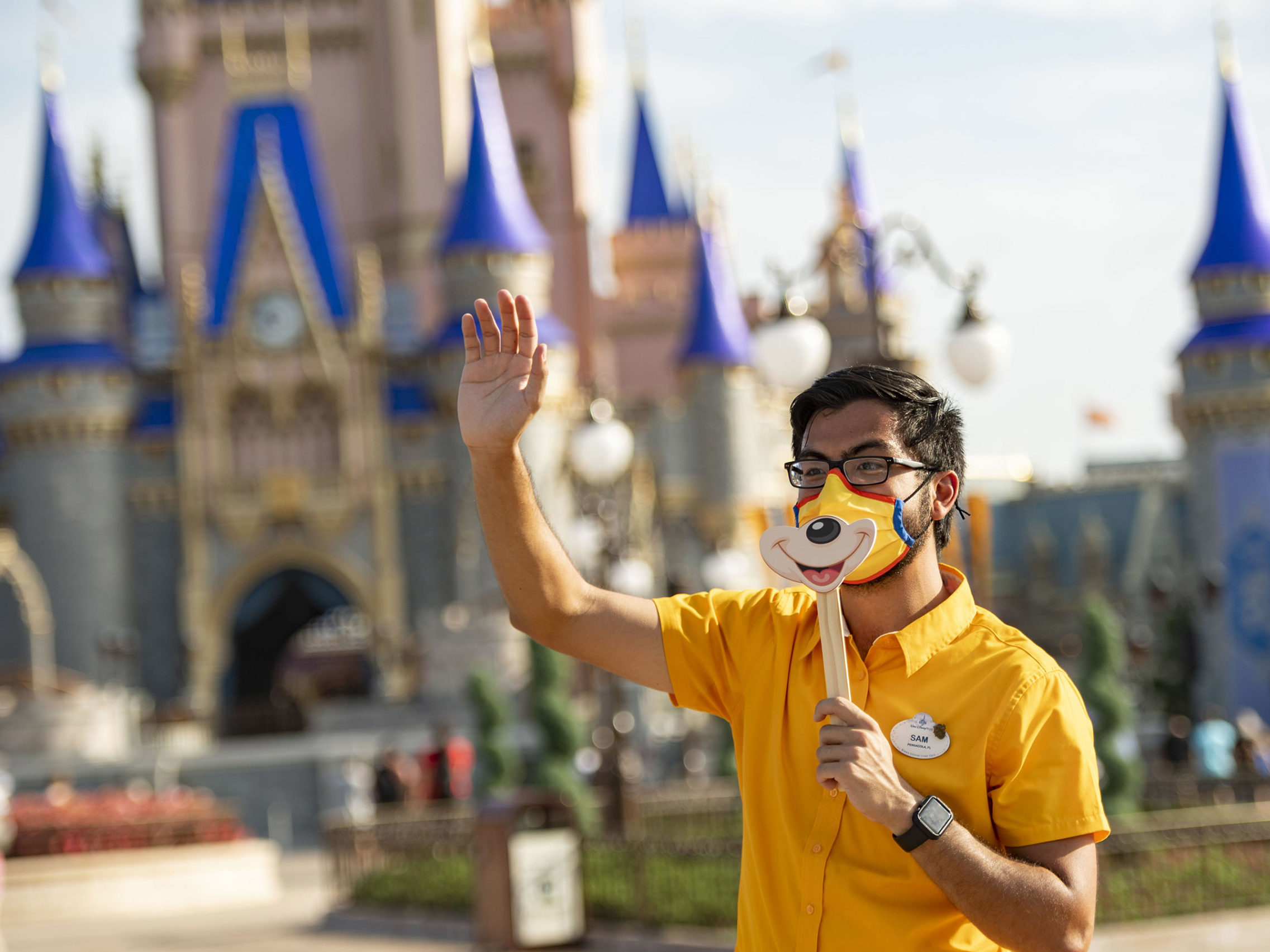 caption: A Disney employee welcomes guests to Walt Disney World Resort on July 11, 2020 in Lake Buena Vista, Fla. Disney has paused its COVID-19 vaccine mandate to comply with a new Florida law.
