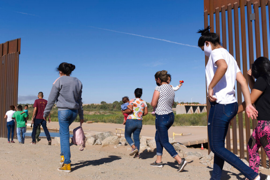 caption: A group of Brazilian migrants make their way around a gap in the U.S.-Mexico border in Yuma, Ariz., seeking asylum in the United States after crossing over from Mexico, June 8, 2021.