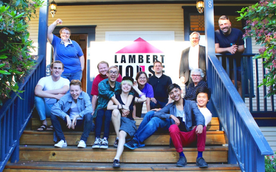 caption: People gather for a group photo on the steps of the Lambert House in Seattle, Washington. 