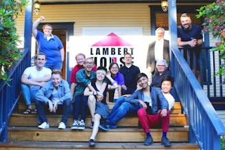 caption: People gather for a group photo on the steps of the Lambert House in Seattle, Washington. 
