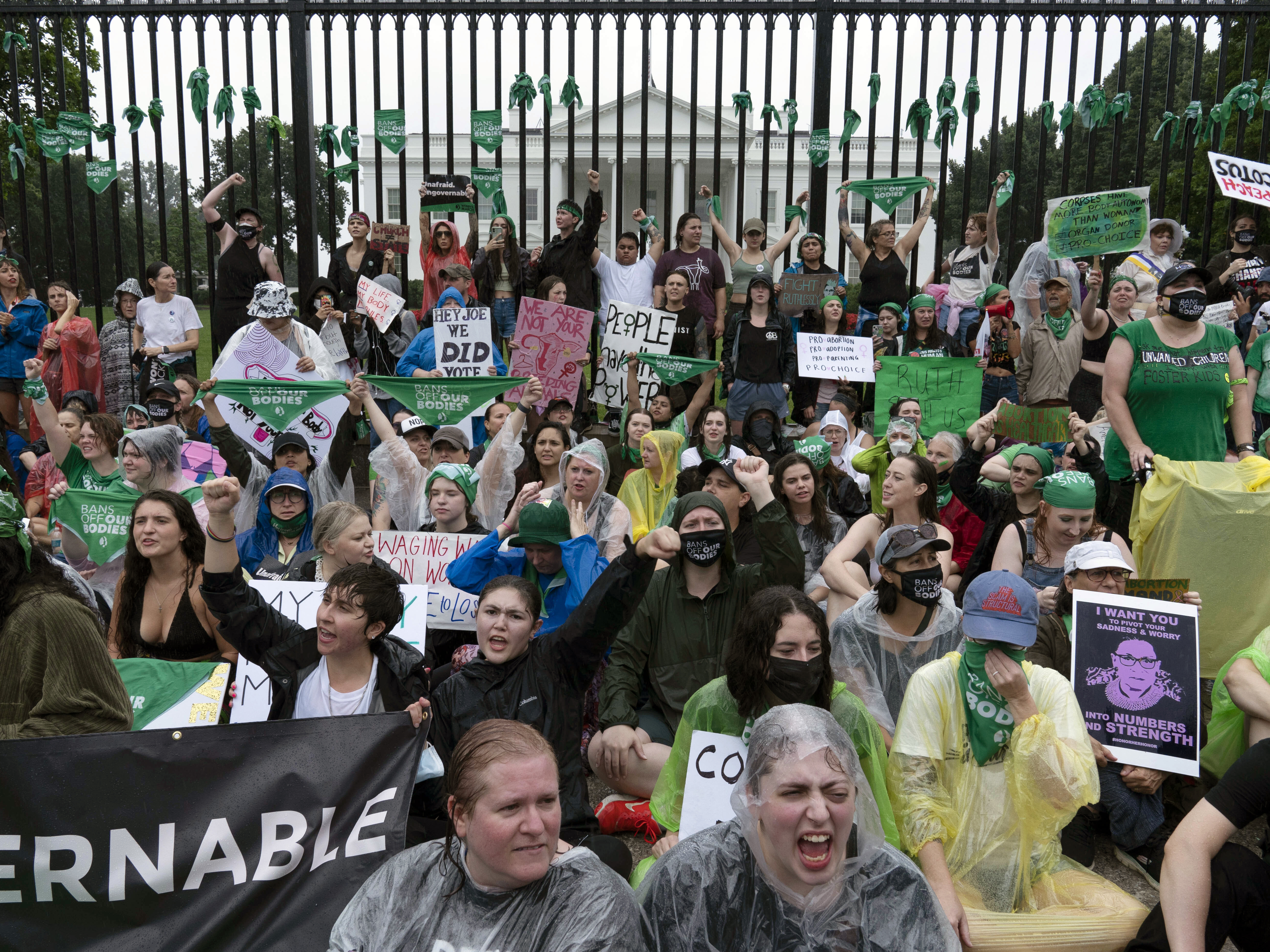 caption: Abortion-rights demonstrators shout slogans after tying green flags to the fence in front of the White House during a protest to pressure the Biden administration to act and protect abortion rights on Saturday.