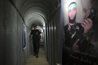 caption: A Palestinian youth walks inside a tunnel used for military exercises during a Hamas-run camp in 2016. Hamas says it has built 300 miles of tunnels under Gaza.