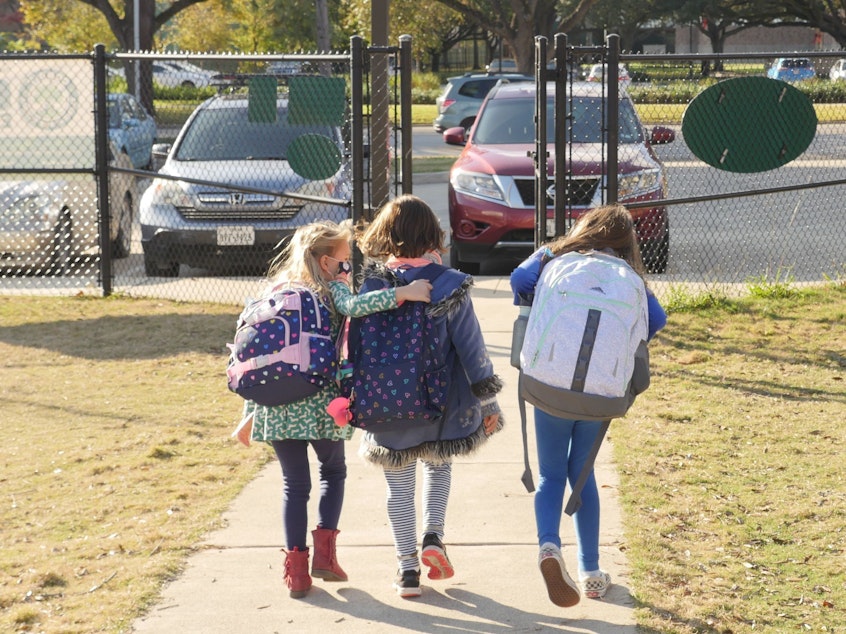 caption: School children wearing facemasks walk outside Condit Elementary School near Houston in December. The U.S. Department of Education announced Friday that it will begin collecting data on the status of in-person learning during the pandemic.