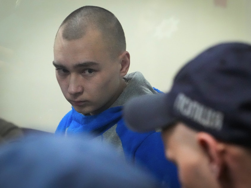 caption: Russian army Sgt. Vadim Shishimarin, 21, is seen behind glass during a court hearing in Kyiv, Ukraine, on Wednesday. Shishimarin pleaded guilty to killing an unarmed Ukrainian civilian.