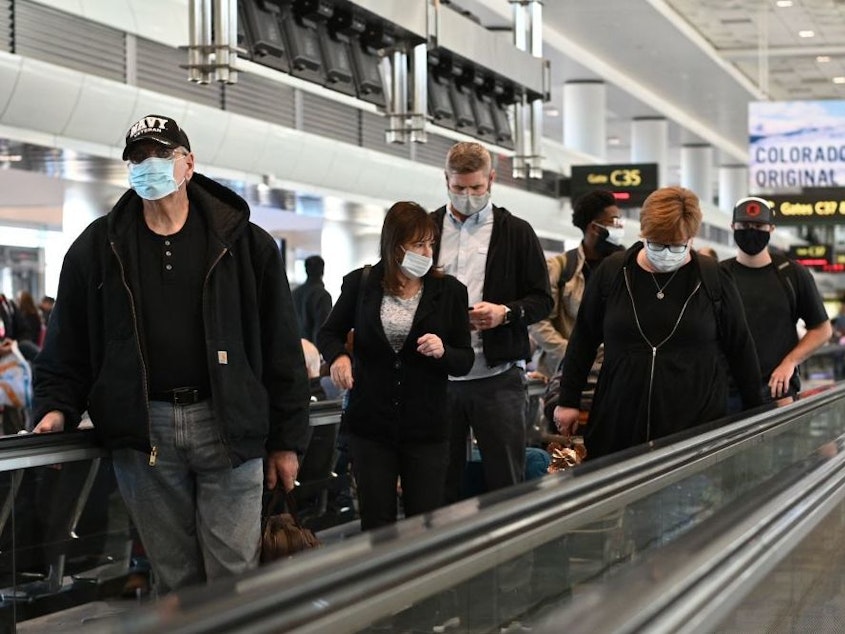 caption: Travelers will need to continue to wear protective face masks at airports, on planes, trains, buses and transit hubs, as the CDC is extending the mask requirement for travelers.
