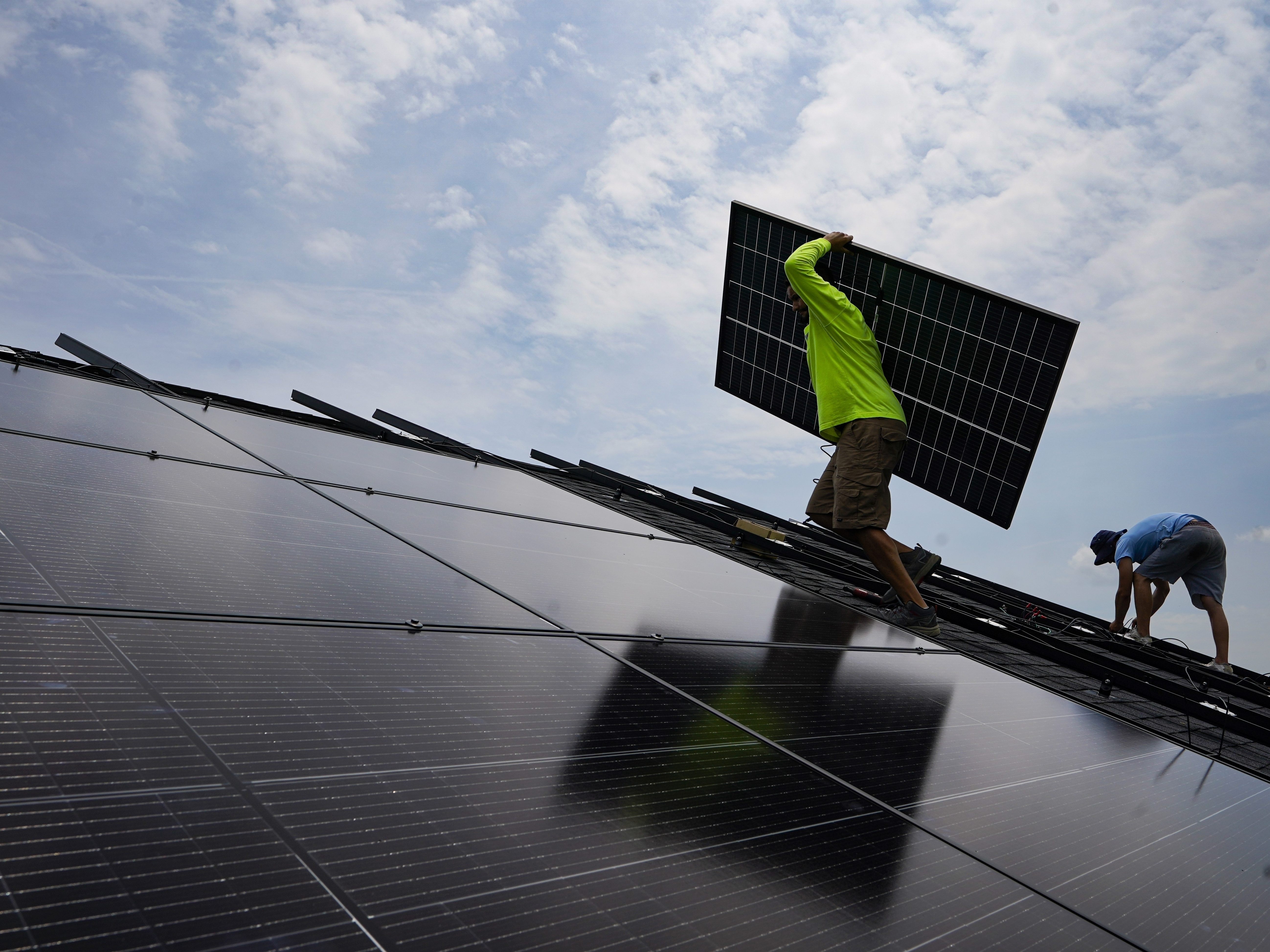 caption: A crew installs a solar array on the roof of a home in Frankfort, Ky., in 2023. 