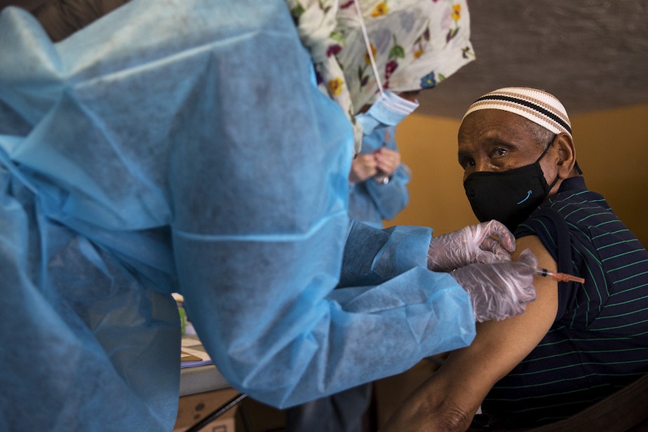 caption: Registered nurse and volunteer Fartun Mohamed, left, administers the first dose of the Moderna Covid-19 vaccine for Enow Ali, right, on Wednesday, February 3, 2021, during a vaccine clinic to vaccinate 100 seniors set up by the Somali Health Board in partnership with the Othello Station Pharmacy and the Brighton Apartments, a complex for seniors, on Rainier Avenue South in Seattle.