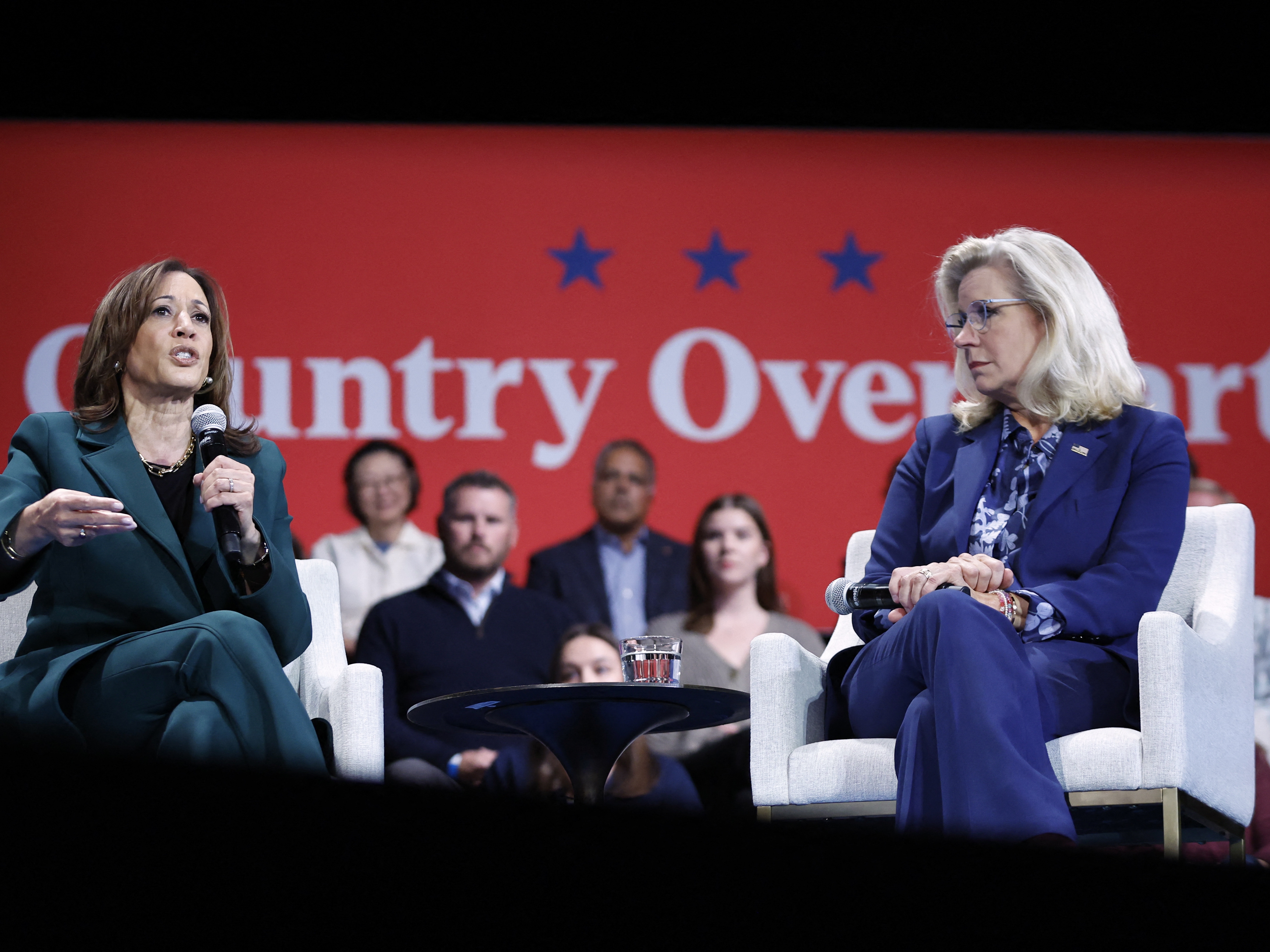 caption: Vice President Harris speaks during a moderated conversation with former Rep. Liz Cheney in Brookfield, Wis., on Monday. They spoke in front of a banner reading "Country Over Party."