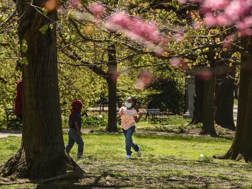 caption: A child wearing a protective mask plays in Brooklyn's Prospect Park in April.