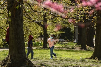 caption: A child wearing a protective mask plays in Brooklyn's Prospect Park in April.