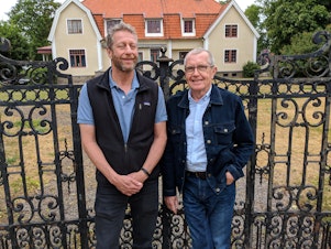 caption: Uri Berliner stands with Swedish journalist Claes Furstenberg in front of the former Furstenberg family home in Kalmar, Sweden.
