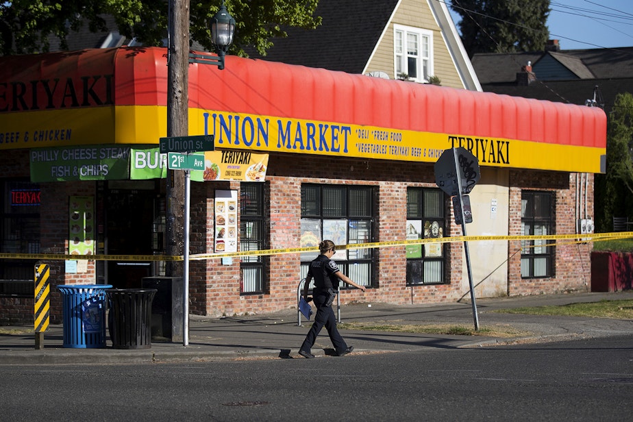 caption: Police officers investigate the scene of a shooting that left one dead and two injured on Friday, May 10, 2019, at the intersection of East Union Street and 21st Avenue in Seattle. 