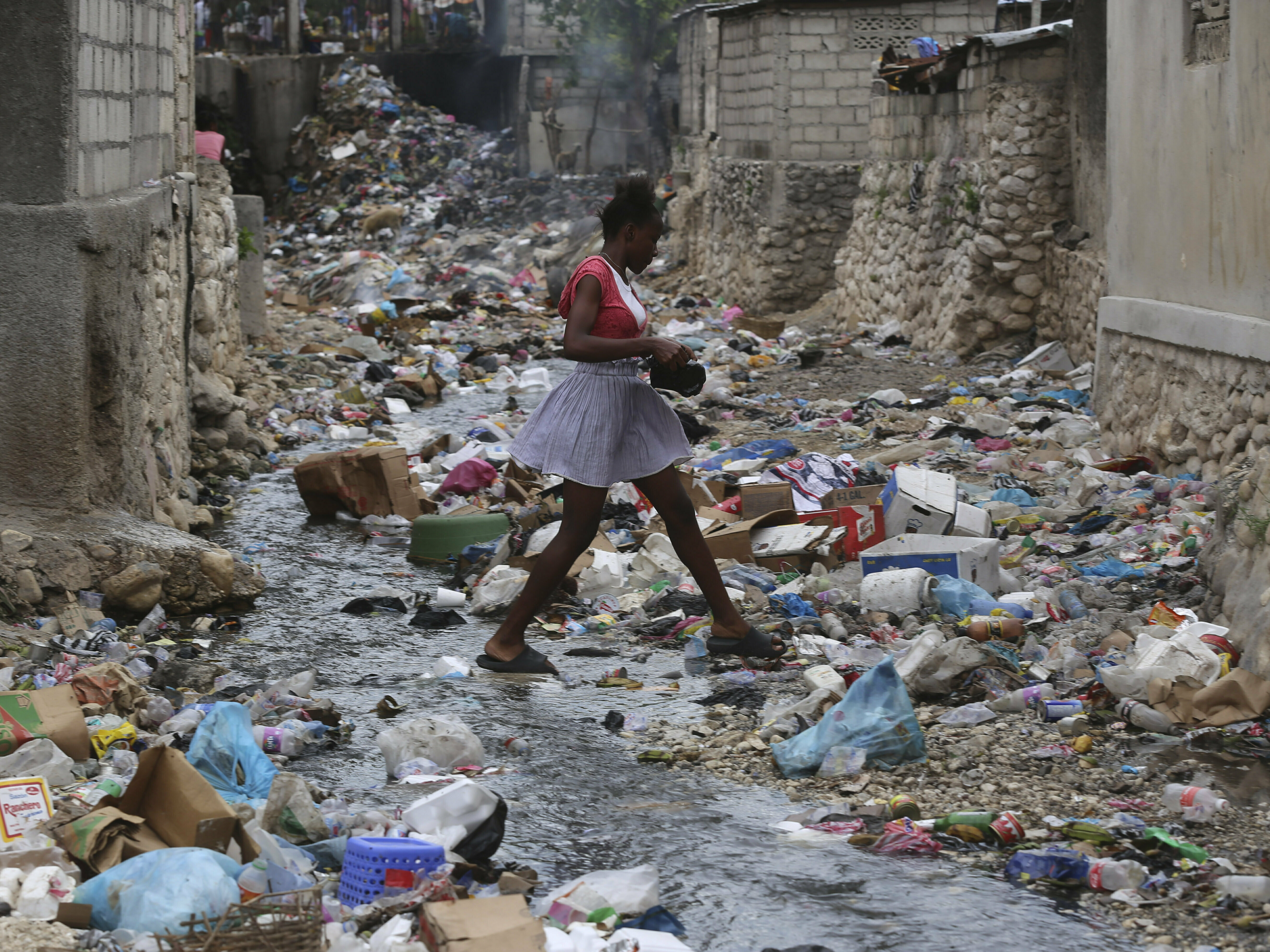 caption: A girl walks through a ravine filled with garbage in Port-au-Prince, Haiti, on July 13.