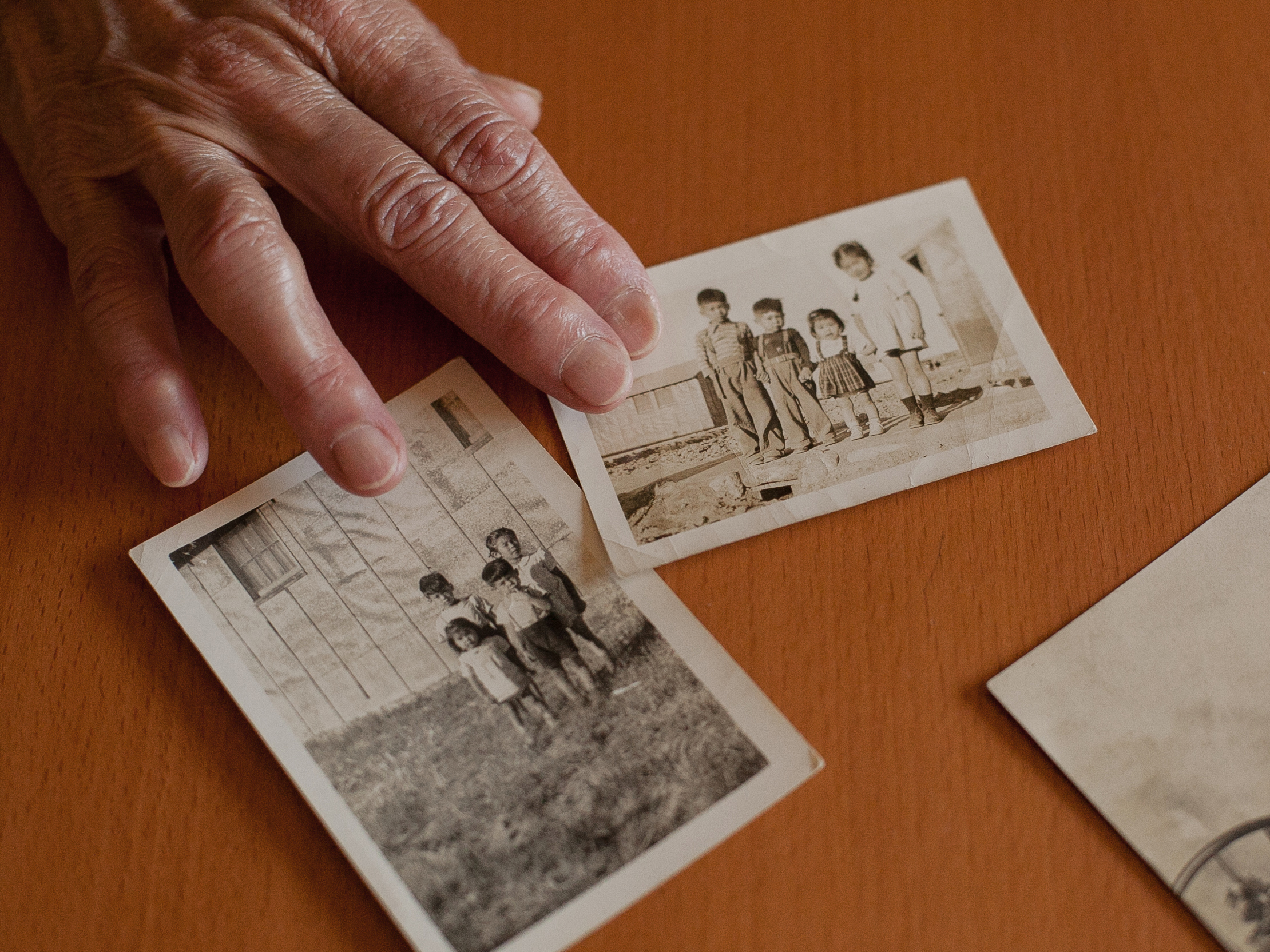 caption: Sharon Sakamoto shows two family photos of Eileen Okada and her other older siblings, who spent part of their childhood living in a barrack behind barbed wire at an Idaho prison camp the U.S. government named the Minidoka War Relocation Center. The third photo is a portrait of their father, Roy Sakamoto, as a young boy.
