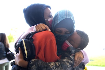 caption: Safia Hussein, center, hugs her sons, 4th-grade student Anwaar Boneya, left, and 2nd-grade student Sabir Boneya, right, before they head into their first day of school at Wing Luke Elementary School on Wednesday, September 1, 2021, along Kenyon Street in Seattle. "It's a little bit scary because of Covid," said Hussein. "But they have to go."
