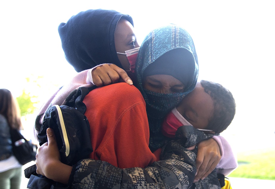 caption: Safia Hussein, center, hugs her sons, 4th-grade student Anwaar Boneya, left, and 2nd-grade student Sabir Boneya, right, before they head into their first day of school at Wing Luke Elementary School on Wednesday, September 1, 2021, along Kenyon Street in Seattle. "It's a little bit scary because of Covid," said Hussein. "But they have to go."