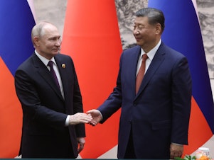 caption: Russian President Vladimir Putin and Chinese President Xi Jinping shake hands during a bilateral meeting on Thursday in Beijing, China.