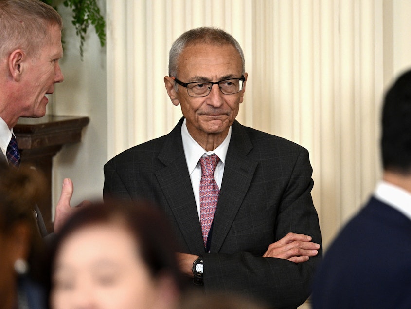 caption: John Podesta looks on during a meeting between President Biden and mayors at the White House on Jan. 19, 2024.
