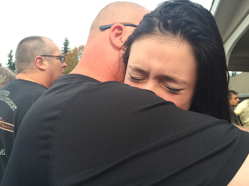 caption: Father and daughter reunite outside a church a few hours after the fatal shooting at Marysville Pilchuck High School.