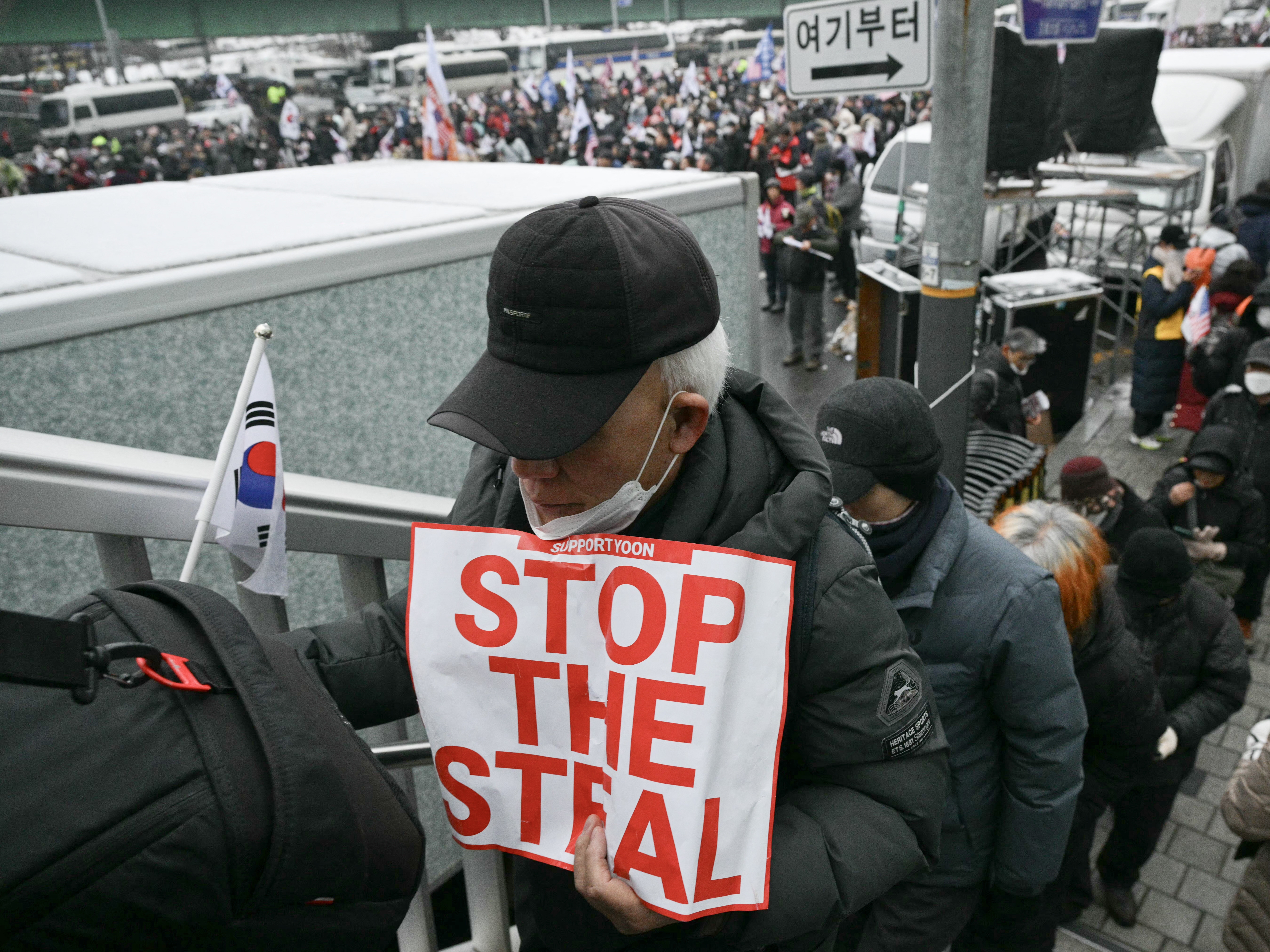 caption: A supporter of impeached South Korean President Yoon Suk Yeol holds a placard reading "Stop the Steal" as he takes part in a rally near Yoon's residence in Seoul on Sunday.