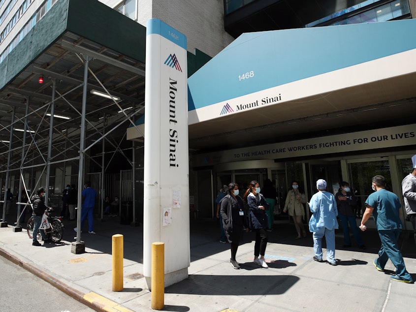 caption: A view of the entrance to Mount Sinai Hospital in New York City on May 14, 2020. Hospital and nursing home workers across New York are required to have at least one dose of a COVID-19 vaccine by Monday, prompting concerns over noncompliance and potential staffing shortages.