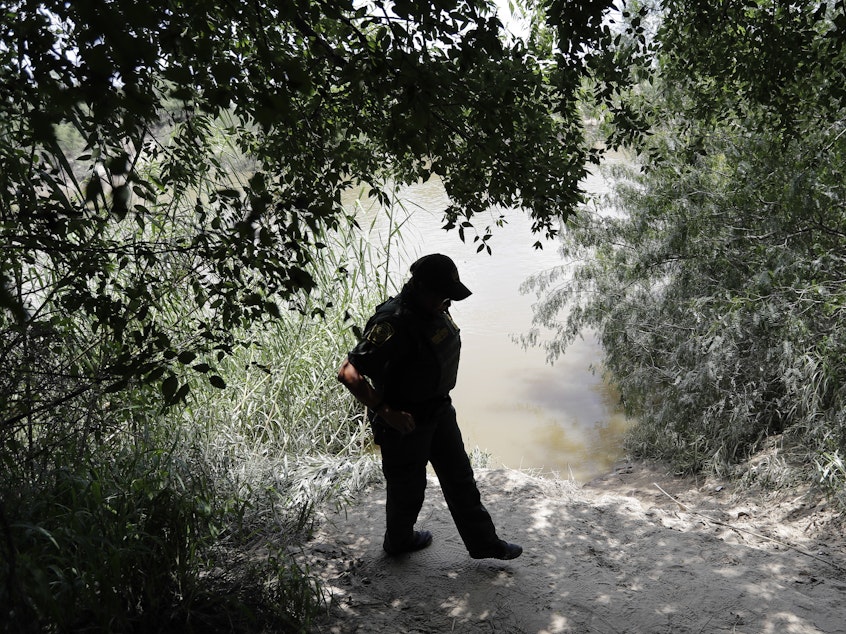 caption: A U.S. Border Patrol agent walks along the banks of the Rio Grande River near McAllen, Texas. Migrant families often cross the river illegally to enter the U.S.