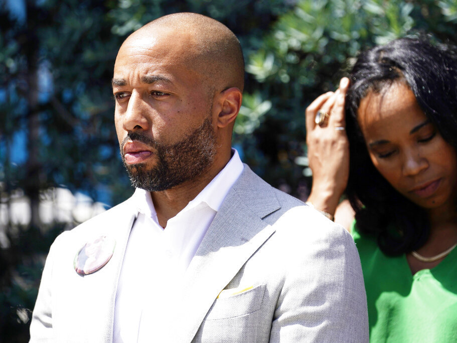 caption: Charles Johnson wears a button with a picture of his wife, Kira, during a press conference announcing a lawsuit outside Cedars-Sinai Medical Center, Wednesday in Los Angeles. Kira Johnson died at the hospital in 2016 from complications after giving birth by cesarean section.
