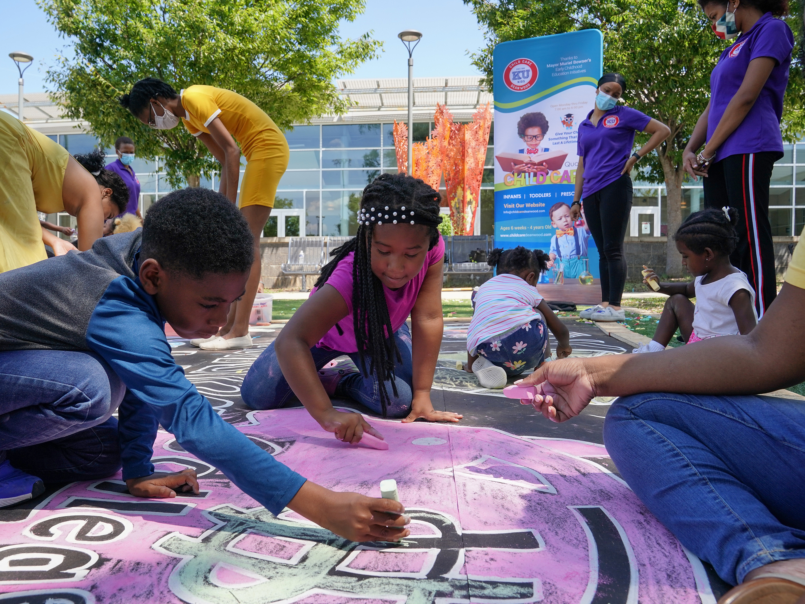 caption: Children and teachers from the KU Kids Deanwood child care center in Washington, D.C., complete a mural in celebration of the launch of the Child Tax Credit.