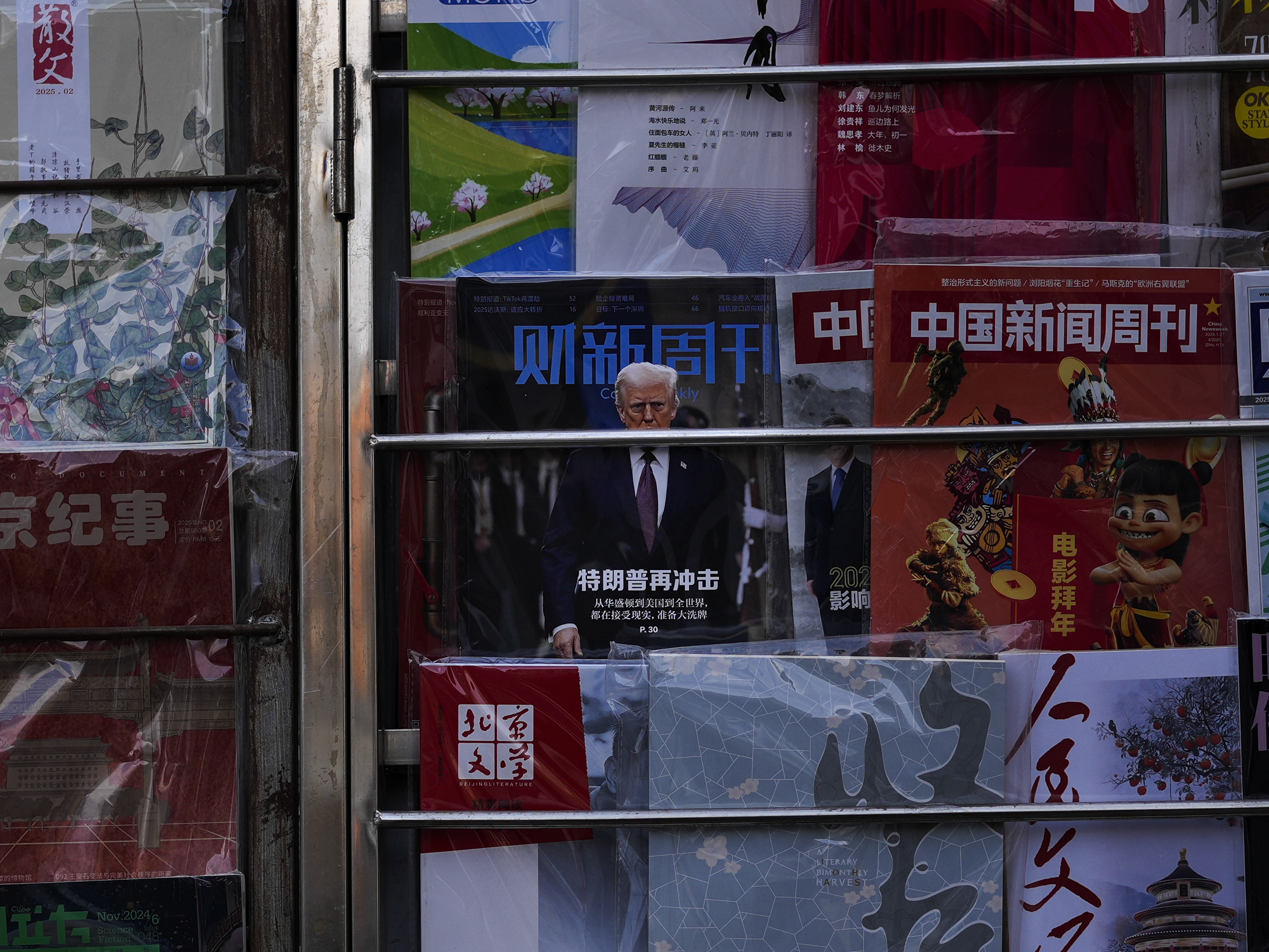 caption: A magazine carrying a front cover of President Donald Trump with the words "Trump shock again" on display with other magazines at a bookstand in Beijing on Tuesday, Feb. 4.