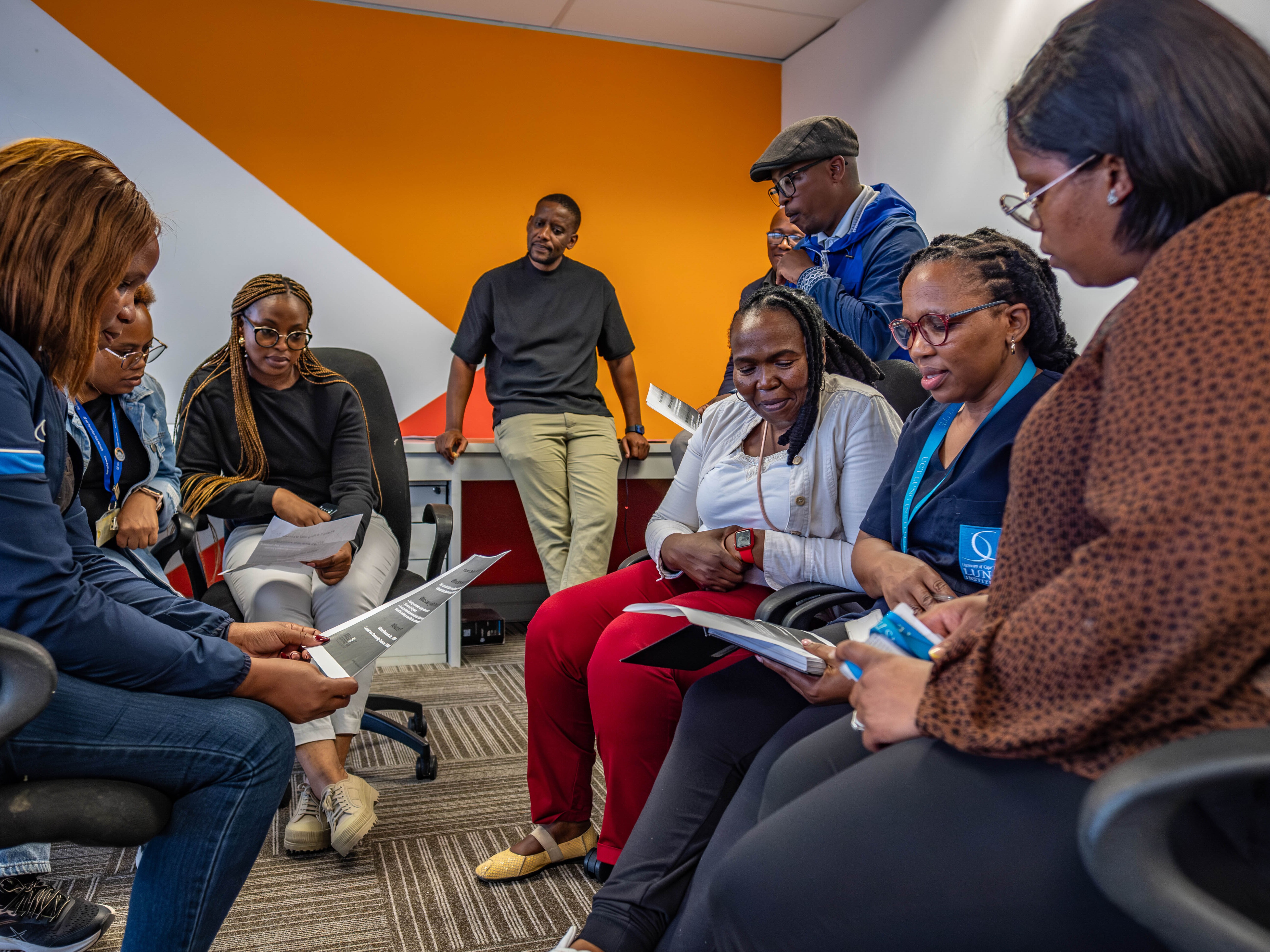 caption: Health workers including community liaison officer Amelia Mfiki (far left) discuss the recruitment of participants for a new HIV vaccine trial in the township of Philippi Village in Cape Town, South Africa.