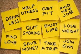 group of sticky yellow adhesive note papers with a list of new year's resolutions on the bulletin board