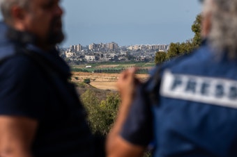 caption: Members of the press wait on an overlook in Sderot, Israel, to report on the fighting in Gaza on Oct. 21.