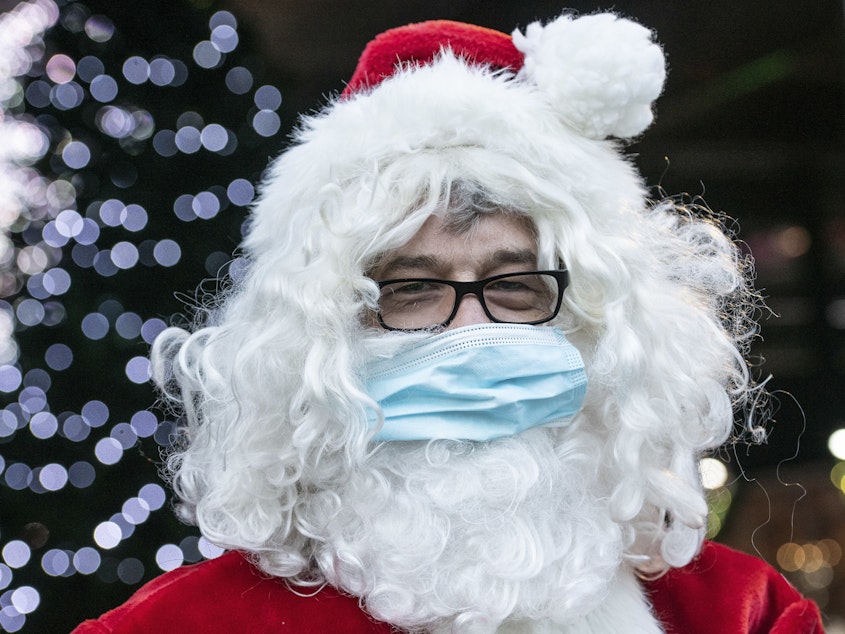 caption: A Santa Claus in Germany wears a surgical mask in December 2020. If you're planning to take the kids to see Santa this year, experts say it's safest to keep everyone's masks on.