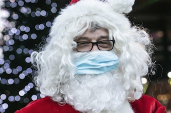 caption: A Santa Claus in Germany wears a surgical mask in December 2020. If you're planning to take the kids to see Santa this year, experts say it's safest to keep everyone's masks on.