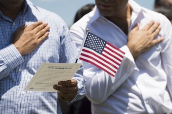 caption: Never before has the U.S. census directly asked for the citizenship status of every person living in every household in the United States. A citizenship question that the Trump administration wants on the 2020 census could change that. Above, newly sworn-in U.S. citizens recite the Pledge of Allegiance during a naturalization ceremony at Mount Vernon in Virginia.