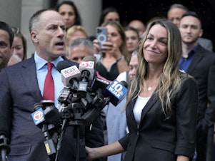 caption: Karen Read, right, smiles as defense attorney David Yannetti, front left, speaks to reporters in front of Norfolk Superior Court in Dedham, Mass., after the judge declared a mistrial on Monday.