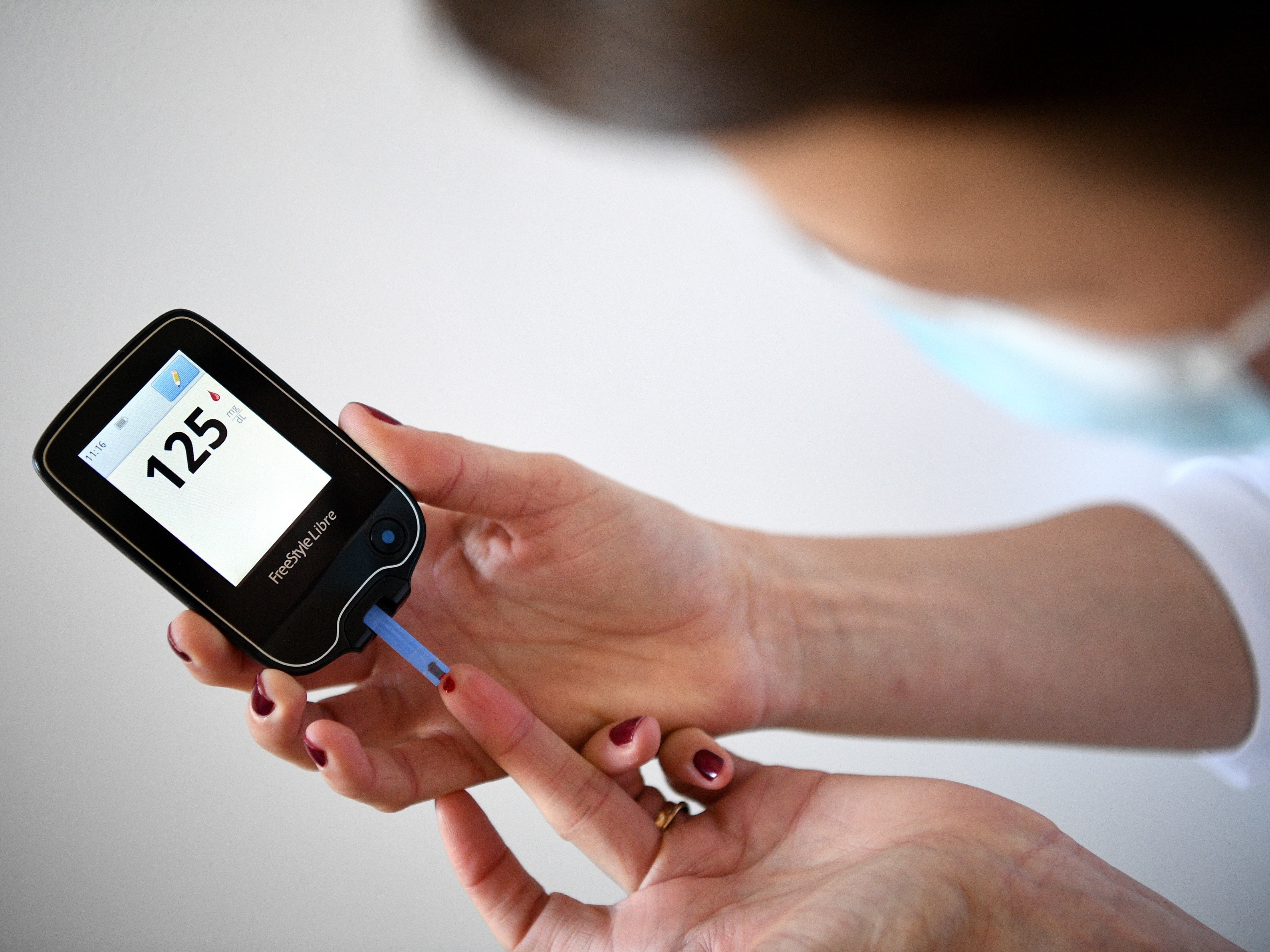caption: A woman with diabetes uses a glucometer to measure the glycemia in her blood on March 24, 2020.
