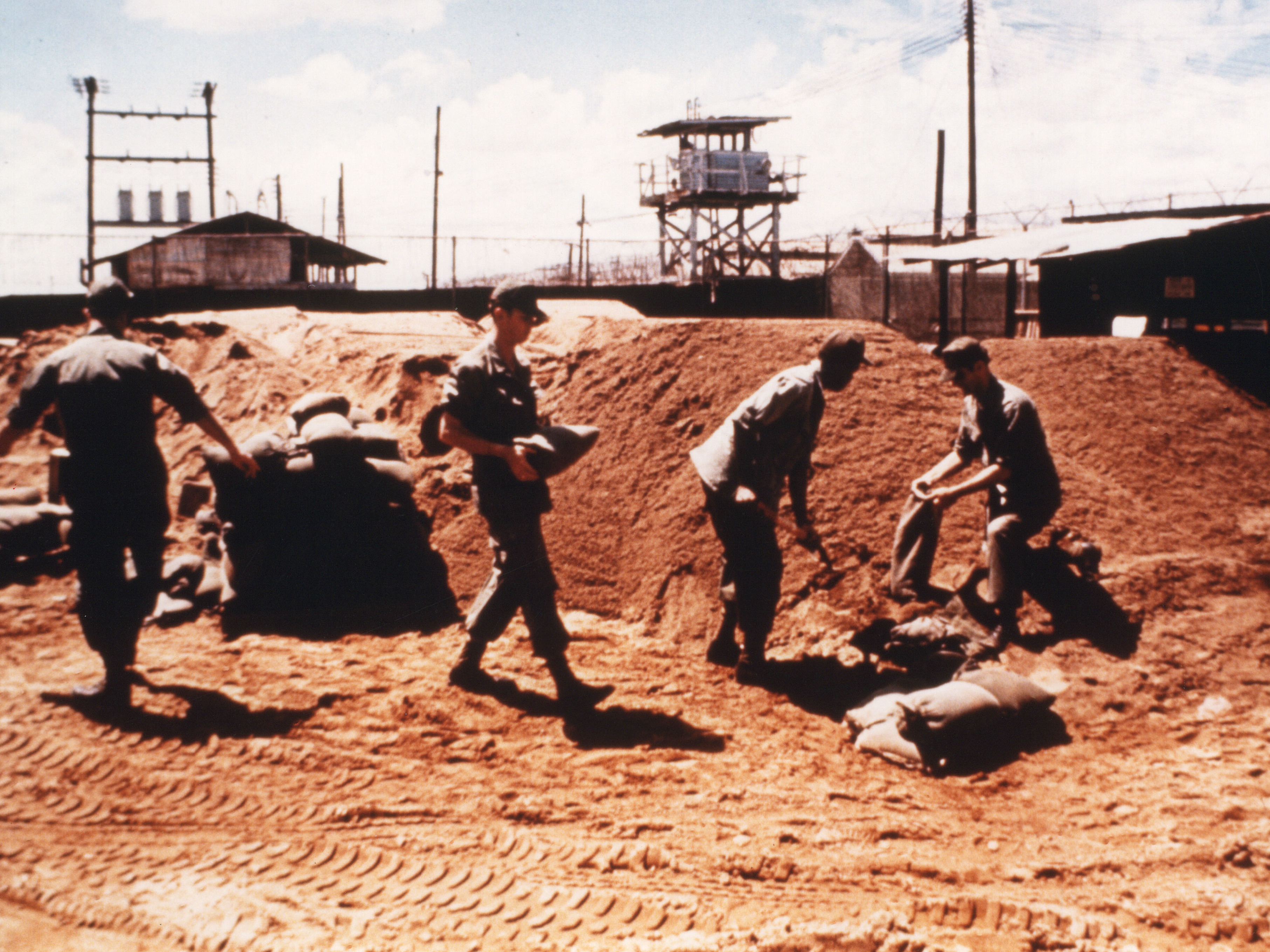 caption: Prisoners on work duty, filling sandbags in the "Big Red" work area.