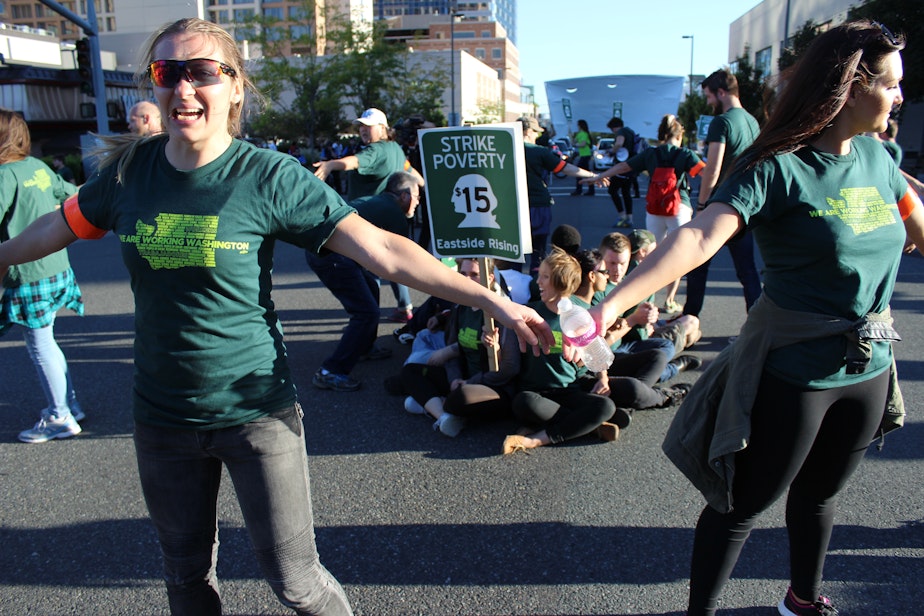 caption: Labor activists from the group Working Washington surround eight protesters who have linked arms in a busy Bellevue intersection Sept. 9, 2014. They were protesting for a raise in the minimum wage.