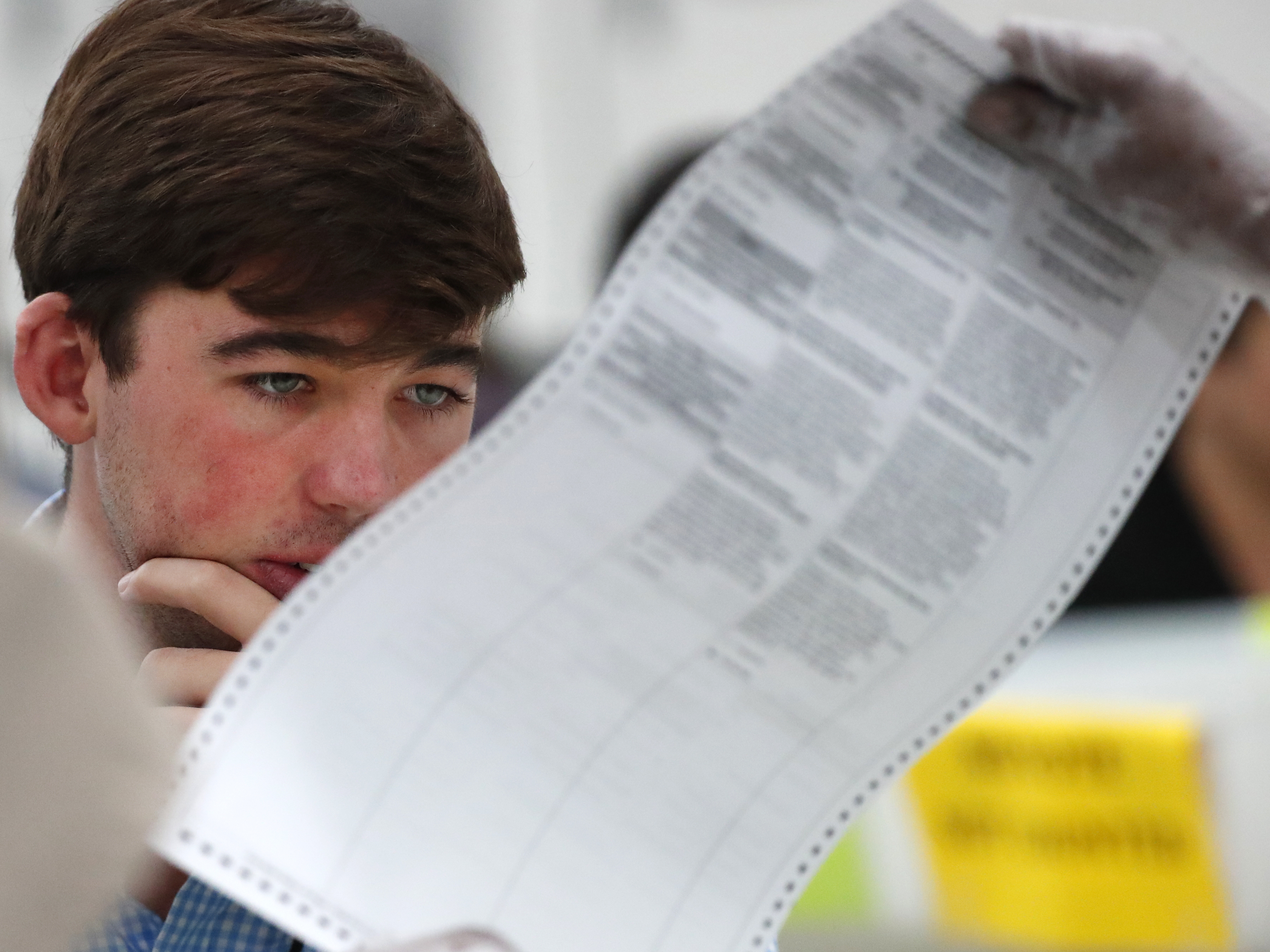 caption: A Republican observer looks at a ballot during a hand recount last November in Broward County, Fla. Florida officials and lawmakers are still learning about cyberattacks there.