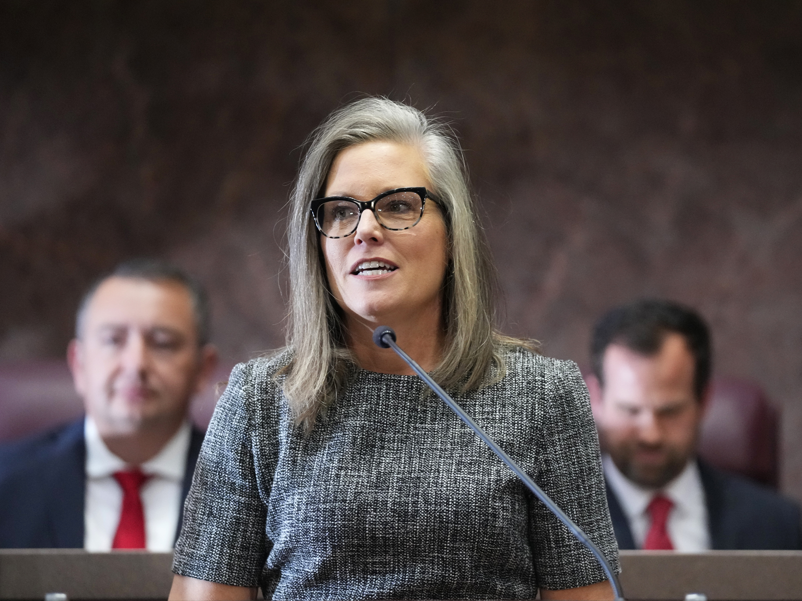 caption: Democratic Arizona Gov. Katie Hobbs, middle, is flanked behind by Arizona House Speaker Ben Toma, left, and Arizona Senate President Warren Petersen, right, at Hobbs' state of the state address on Jan. 9, 2023, in Phoenix.