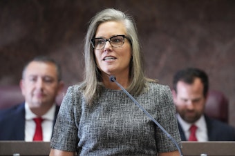 caption: Democratic Arizona Gov. Katie Hobbs, middle, is flanked behind by Arizona House Speaker Ben Toma, left, and Arizona Senate President Warren Petersen, right, at Hobbs' state of the state address on Jan. 9, 2023, in Phoenix.