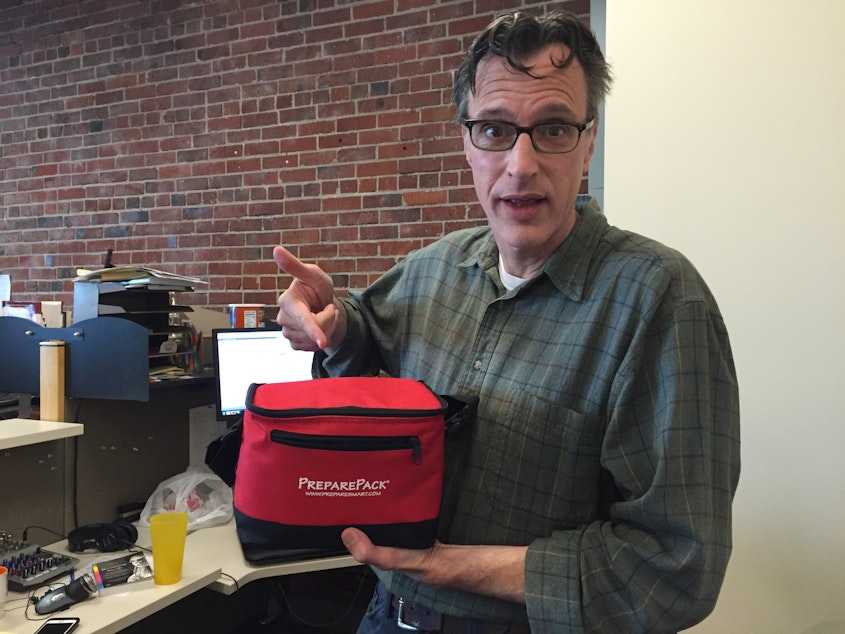 caption: Bill Radke shows off the emergency kits we have for everyone at KUOW (but that's not enough to last us in a major catastrophe).