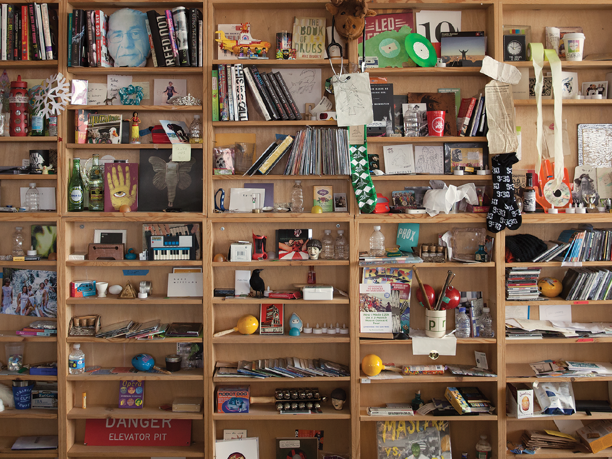 caption: The bric-a-brac-stacked shelves of the Tiny Desk.