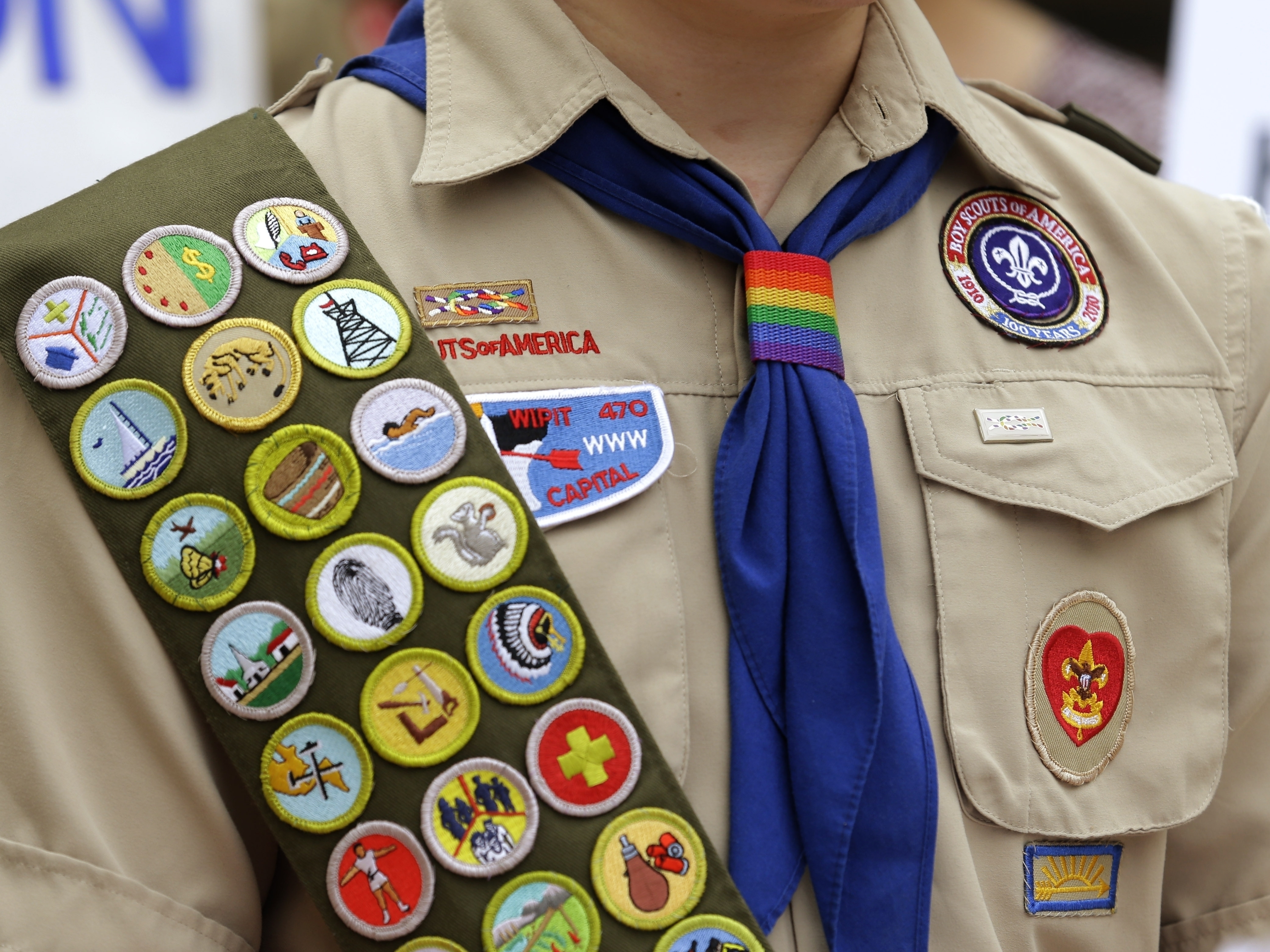 caption: FILE - Merit badges and a rainbow-colored neckerchief slider are affixed on a Boy Scout uniform. The U.S. organization, which now welcomes girls into the program and allows them to work toward the coveted Eagle Scout rank, announced May 7, 2024, that it would change its name to Scouting America as it focuses on inclusion.