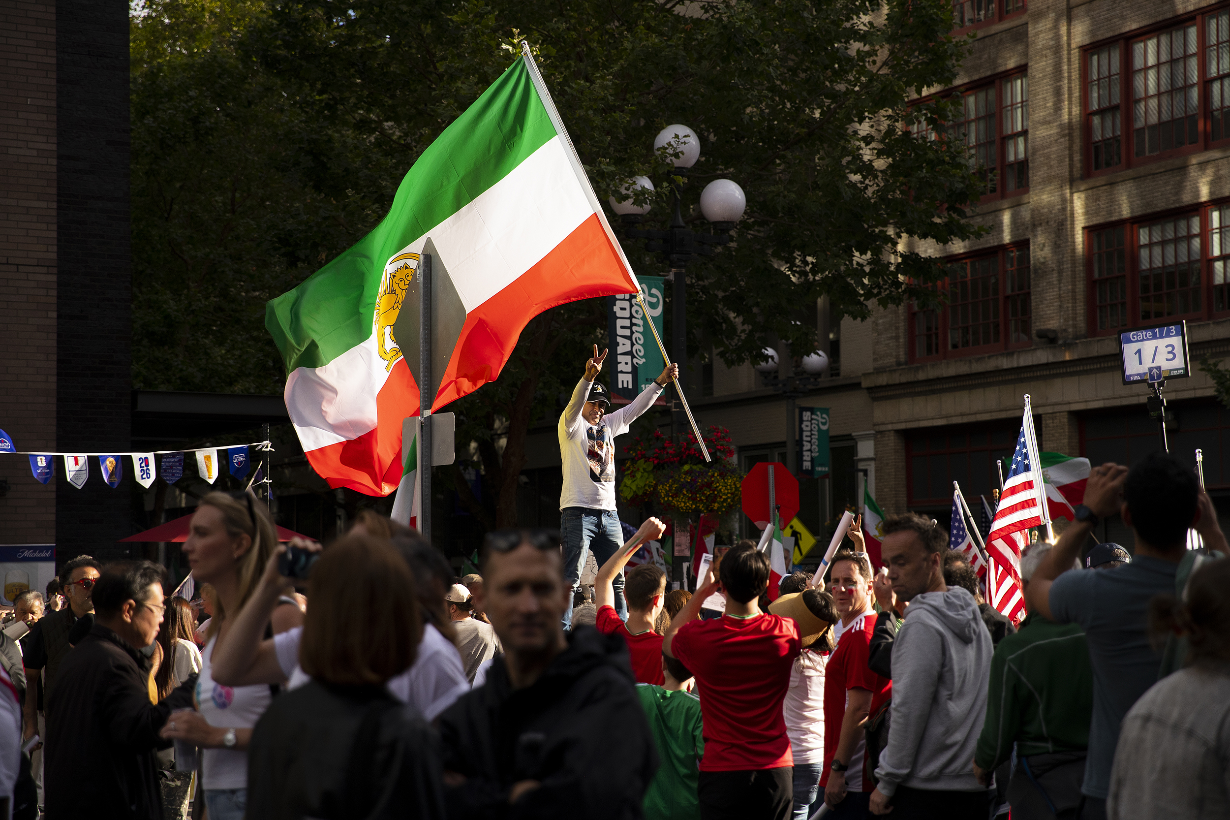 caption: Demonstrators protesting the Islamic Republic regime in Iran gather as soccer fans walk toward the stadium ahead of the FIFA World Cup match between Egypt and Iran, on Friday, June 26, 2026, in Seattle.