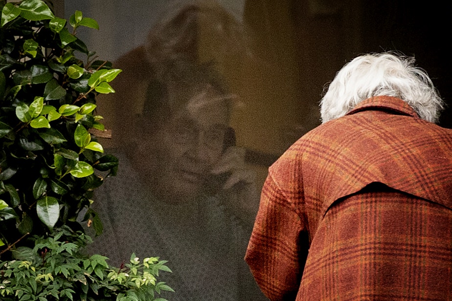 caption: Dorothy Campbell talks to her husband, Gene Campbell, on the phone through his window at the Life Care Center of Kirkland on Thursday, March 5, 2020, in Kirkland. Dorothy's son Charlie Campbell came from Silver City, New Mexico, to bring his mother to see his father. "It’s kind of tough but it’s the best we can do at this point," he said. 