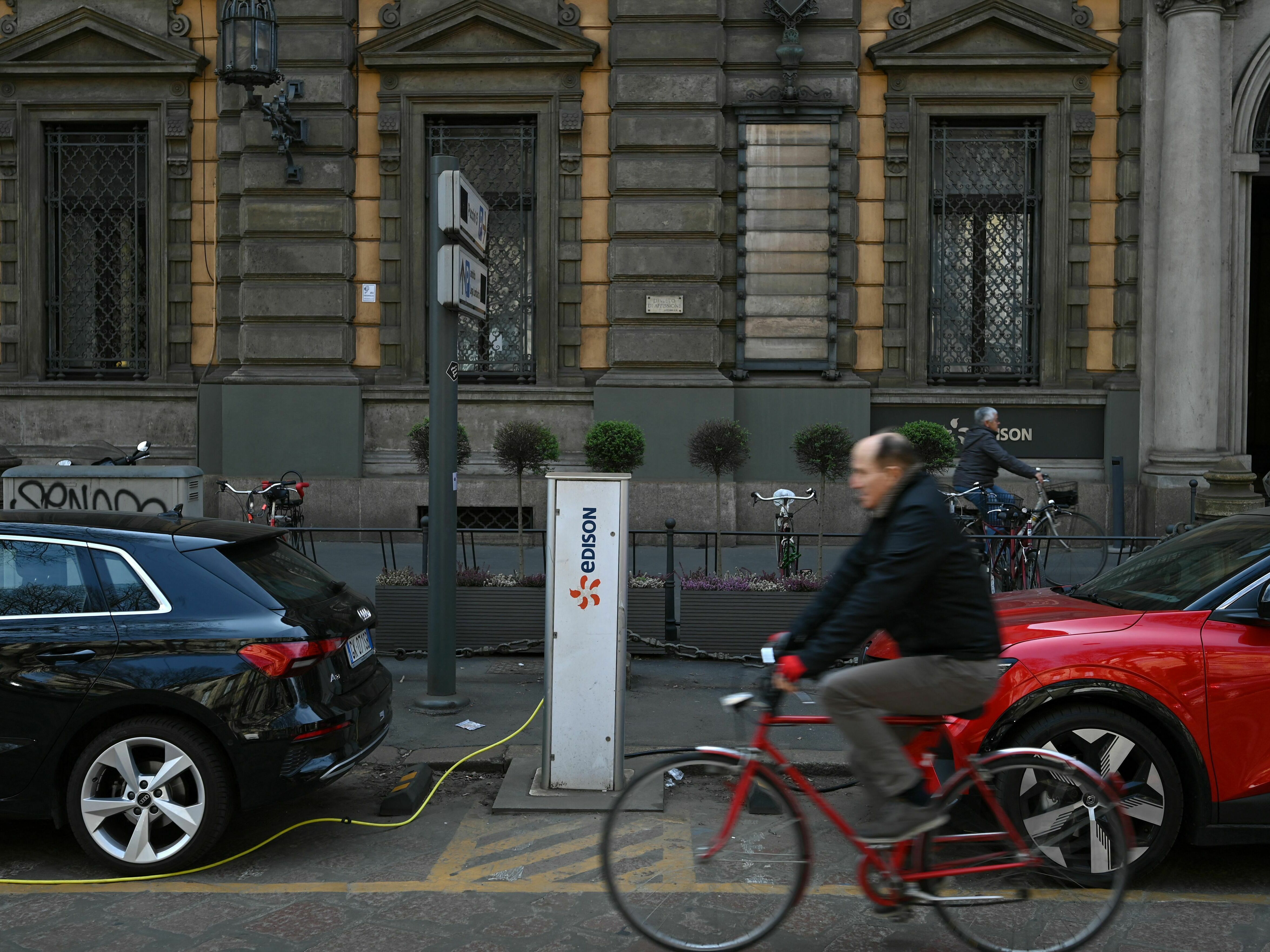 caption: Electric cars charge at a hub in downtown Milan on March 23. Starting in 2035, all cars sold in the European Union will be zero-emission vehicles.