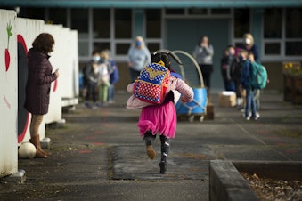caption: Alayna Holmes, a first-grade student at Northgate Elementary, runs toward her classmates on Monday, April 5, 2021, on the first day of in-person learning at the school in Seattle. 